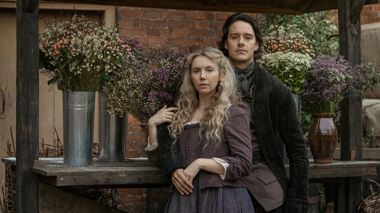 A man and a woman stand in front of a flower cart